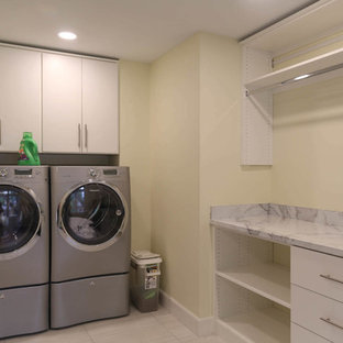 他の地域の中サイズのトランジショナルスタイルのおしゃれな家事室 (フラットパネル扉のキャビネット、白いキャビネット、ラミネートカウンター、磁器タイルの床、左右配置の洗濯機・乾燥機、白い床、マルチカラーのキッチンカウンター、ベージュの壁) の写真