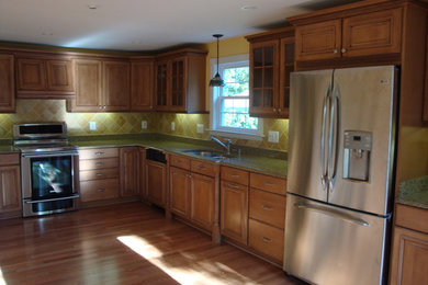Mid-sized elegant l-shaped medium tone wood floor and brown floor enclosed kitchen photo in Baltimore with a double-bowl sink, raised-panel cabinets, medium tone wood cabinets, granite countertops, beige backsplash, ceramic backsplash, stainless steel appliances, no island and beige countertops