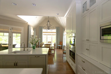 Eat-in kitchen - large transitional l-shaped medium tone wood floor and brown floor eat-in kitchen idea in Charlotte with an undermount sink, shaker cabinets, white cabinets, quartz countertops, white backsplash, stainless steel appliances, two islands and white countertops