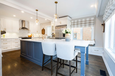 Large transitional l-shaped dark wood floor and brown floor enclosed kitchen photo in Toronto with recessed-panel cabinets, an island, an undermount sink, stainless steel appliances, white cabinets, quartzite countertops, white backsplash, marble backsplash and white countertops
