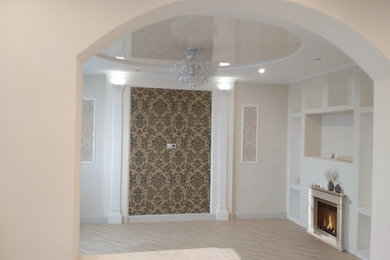 Пример оригинального дизайна: гостиная комната среднего размера в классическом стиле с полом из ламината, стандартным камином, фасадом камина из штукатурки и бежевым полом