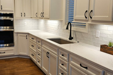 Inspiration for a large timeless medium tone wood floor kitchen remodel in Kansas City with a single-bowl sink, flat-panel cabinets, quartz countertops, white backsplash, stainless steel appliances, an island and yellow countertops