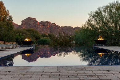 Example of a large trendy backyard stone and rectangular infinity pool landscaping design in Phoenix