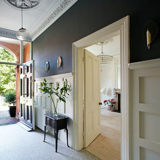 Esempio di un corridoio chic di medie dimensioni con pareti grigie, pavimento in granito e una porta nera
