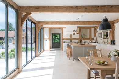 L-shaped eat-in kitchen in West Midlands with a farmhouse sink, shaker cabinets, grey cabinets, wood benchtops, white splashback, with island, beige floor and brown benchtop.