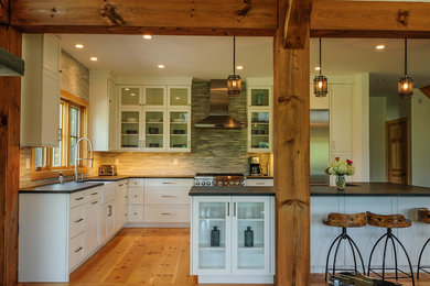Open concept kitchen - cottage l-shaped medium tone wood floor and beige floor open concept kitchen idea in New York with a farmhouse sink, shaker cabinets, white cabinets, granite countertops, gray backsplash, marble backsplash, stainless steel appliances, an island and black countertops