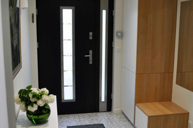 Aménagement d'un hall d'entrée contemporain de taille moyenne avec un mur beige, un sol en carrelage de céramique, une porte double, une porte noire et un sol gris.