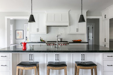 Open concept kitchen - mid-sized transitional dark wood floor and brown floor open concept kitchen idea in San Francisco with a farmhouse sink, beaded inset cabinets, white cabinets, soapstone countertops, white backsplash, stone tile backsplash, paneled appliances, an island and black countertops