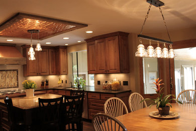 Inspiration for a rustic u-shaped eat-in kitchen remodel in Minneapolis with an undermount sink, raised-panel cabinets, medium tone wood cabinets, quartzite countertops, multicolored backsplash, mosaic tile backsplash and stainless steel appliances
