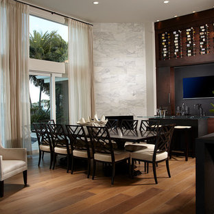 This is an example of a large tropical open plan dining in Tampa with white walls, light hardwood floors, a corner fireplace and a stone fireplace surround.