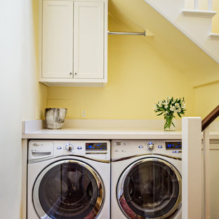 Small traditional single-wall utility room in Nashville with recessed-panel cabinets, white cabinets, laminate countertops, yellow walls, medium hardwood flooring and a side by side washer and dryer.