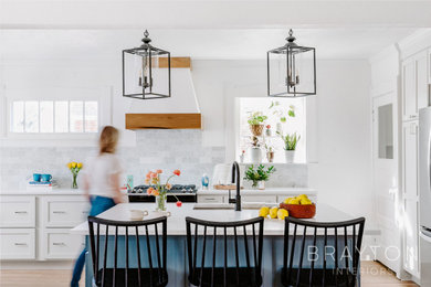 Inspiration for a craftsman light wood floor eat-in kitchen remodel in Denver with an undermount sink, shaker cabinets, white cabinets, quartz countertops, multicolored backsplash, marble backsplash, stainless steel appliances, an island and white countertops