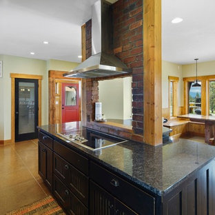 Cette photo montre une grande arrière-cuisine craftsman en L avec un évier encastré, un placard avec porte à panneau encastré, des portes de placard en bois vieilli, un plan de travail en granite, une crédence multicolore, une crédence en ardoise, un électroménager noir, béton au sol, un îlot central, un sol beige et un plan de travail multicolore.