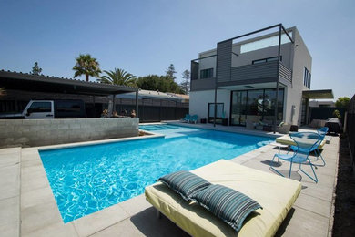 Inspiration for a large modern backyard l-shaped pool in San Diego with concrete pavers.