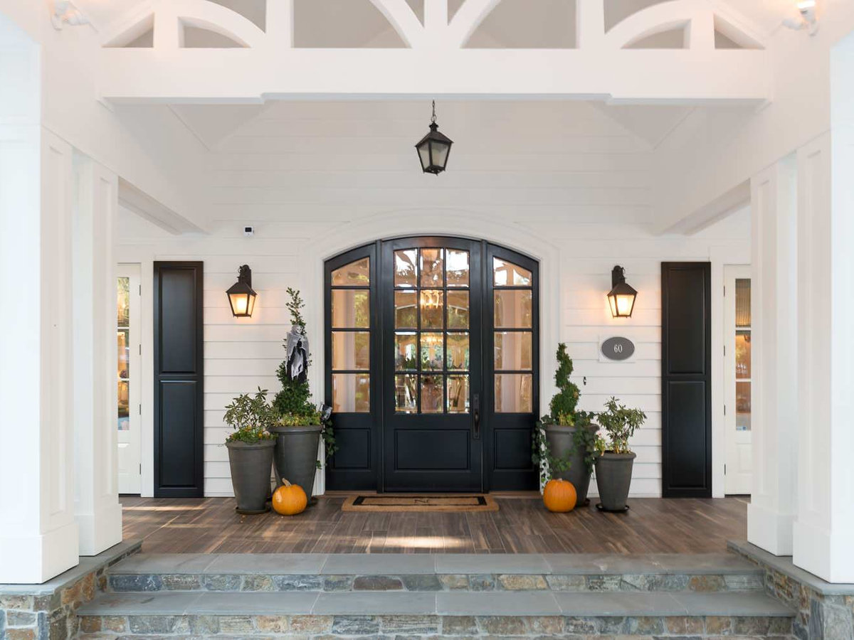 Arched black front door flanked by potted plants