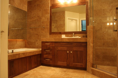 Example of a large trendy master marble tile marble floor and beige floor corner shower design in San Diego with shaker cabinets, brown cabinets, beige walls, a drop-in sink, marble countertops and a hinged shower door
