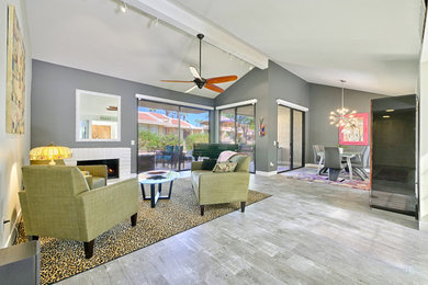 Example of a mid-sized trendy open concept laminate floor and gray floor living room design in Los Angeles with gray walls, a standard fireplace and no tv