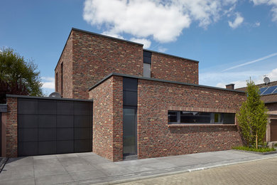 Mittelgroßes, Zweistöckiges Industrial Einfamilienhaus mit Backsteinfassade, bunter Fassadenfarbe und Flachdach in Köln