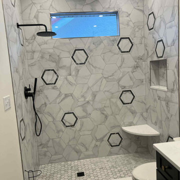 Premium finishes: Matte black shower set, brushed gold sink fixtures.