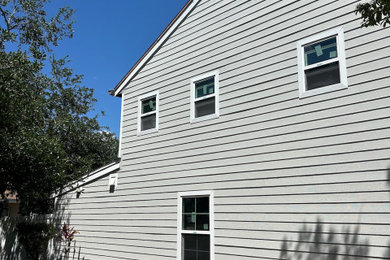 Large minimalist gray concrete fiberboard exterior home photo in Tampa with a shingle roof and a black roof