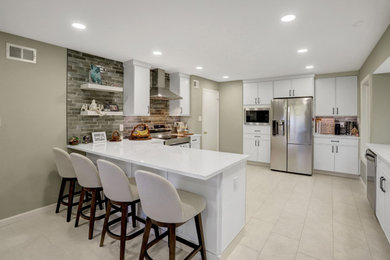 Example of a trendy porcelain tile and white floor eat-in kitchen design in DC Metro with an undermount sink, shaker cabinets, white cabinets, quartz countertops, green backsplash, porcelain backsplash, stainless steel appliances, a peninsula and white countertops