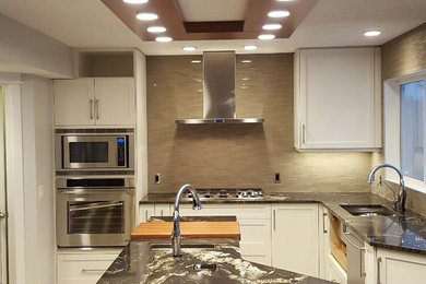 Example of a mid-sized minimalist u-shaped eat-in kitchen design in Calgary with shaker cabinets, white cabinets and an island