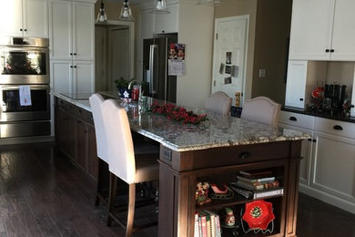 Eat-in kitchen - mid-sized traditional single-wall dark wood floor and brown floor eat-in kitchen idea in Other with shaker cabinets, white cabinets, granite countertops, beige backsplash, stainless steel appliances and an island