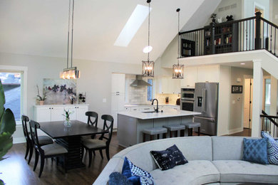 Eat-in kitchen - contemporary single-wall dark wood floor, brown floor and vaulted ceiling eat-in kitchen idea in Minneapolis with a double-bowl sink, flat-panel cabinets, white cabinets, granite countertops, gray backsplash, stainless steel appliances, an island and white countertops