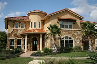 Example of a large tuscan multicolored two-story stone exterior home design in Austin with a hip roof