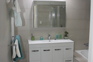 This is an example of a modern bathroom in Brisbane with white cabinets and ceramic floors.