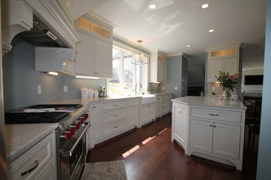 Large traditional l-shaped eat-in kitchen in Boston with a farmhouse sink, beaded inset cabinets, white cabinets, marble benchtops, stainless steel appliances, dark hardwood floors, with island and brown floor.