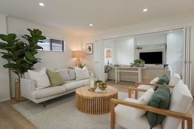 Beach style living room in Gold Coast - Tweed with light hardwood floors and a wall-mounted tv.