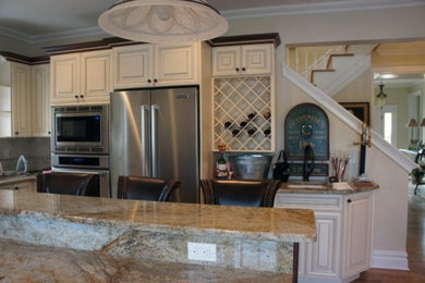 Mid-sized l-shaped medium tone wood floor eat-in kitchen photo in New York with a drop-in sink, white cabinets, quartzite countertops, beige backsplash, stainless steel appliances and an island