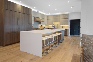 Large contemporary l-shaped open plan kitchen in San Francisco with an undermount sink, flat-panel cabinets, dark wood cabinets, quartzite benchtops, stainless steel appliances, light hardwood floors, with island and beige floor.