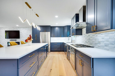 Inspiration for a large modern l-shaped bamboo floor, brown floor and vaulted ceiling eat-in kitchen remodel in DC Metro with an undermount sink, shaker cabinets, blue cabinets, quartzite countertops, white backsplash, porcelain backsplash, stainless steel appliances, an island and white countertops