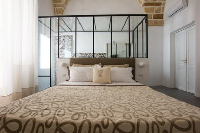 Ejemplo de dormitorio abovedado con paredes blancas y suelo gris
