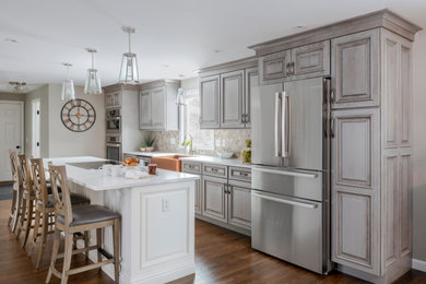 This is an example of a large single-wall kitchen/diner in Providence with a belfast sink, raised-panel cabinets, distressed cabinets, engineered stone countertops, multi-coloured splashback, mosaic tiled splashback, stainless steel appliances, vinyl flooring, an island and white worktops.