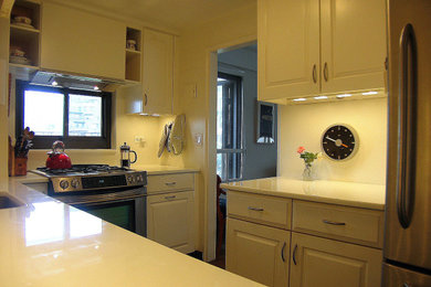 Mid-sized trendy u-shaped ceramic tile and brown floor eat-in kitchen photo with an undermount sink, raised-panel cabinets, white cabinets, quartz countertops, white backsplash, stainless steel appliances, ceramic backsplash, white countertops and no island