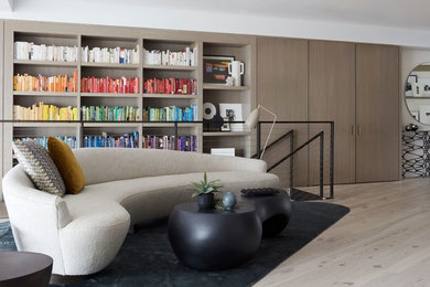 Trendy open concept light wood floor and beige floor family room library photo in New York with white walls, no fireplace and no tv