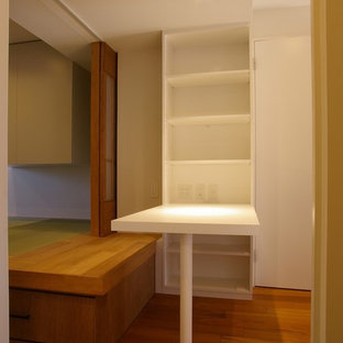 This is an example of a small modern study in Other with white walls, plywood flooring, a built-in desk and brown floors.