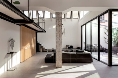 Esempio di un grande soggiorno minimal stile loft con pareti bianche, pavimento in gres porcellanato, pavimento grigio e travi a vista
