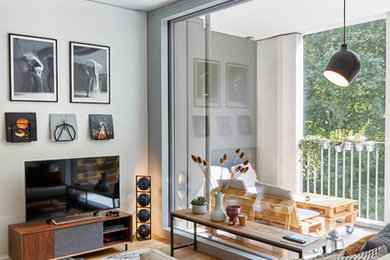 Modernes Wohnzimmer mit weißer Wandfarbe, braunem Holzboden, freistehendem TV und braunem Boden in München