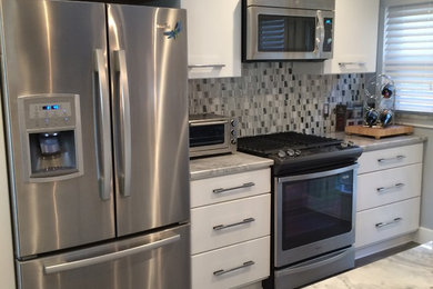 Example of a mid-sized minimalist single-wall marble floor open concept kitchen design in Detroit with a peninsula, flat-panel cabinets, white cabinets, marble countertops, metallic backsplash, ceramic backsplash, stainless steel appliances and an undermount sink