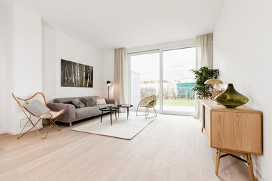 This is an example of a mid-sized scandinavian enclosed family room in Hamburg with white walls, light hardwood floors, no fireplace, no tv and beige floor.