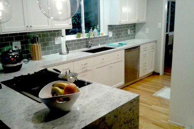 Inspiration for a mid-sized transitional l-shaped light wood floor enclosed kitchen remodel in San Francisco with an undermount sink, shaker cabinets, white cabinets, quartz countertops, gray backsplash, subway tile backsplash, stainless steel appliances and a peninsula