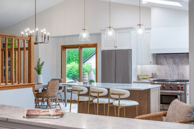 Transitional vaulted ceiling kitchen photo in Minneapolis with white cabinets, an island and white countertops