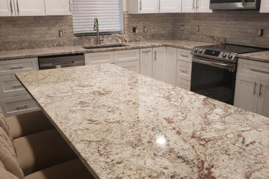 Example of a kitchen design in Salt Lake City with an undermount sink, shaker cabinets, white cabinets, granite countertops, beige backsplash, cement tile backsplash, stainless steel appliances and an island