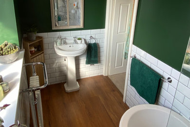 Photo of a classic half tiled bathroom with a claw-foot bath, a shower/bath combination, white tiles, cement tiles, green walls, cork flooring, a pedestal sink and a single sink.
