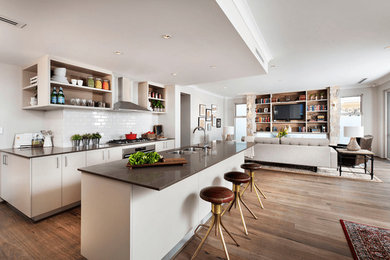 Mid-sized trendy single-wall medium tone wood floor and brown floor open concept kitchen photo in Austin with a double-bowl sink, flat-panel cabinets, white cabinets, white backsplash, subway tile backsplash, stainless steel appliances, an island and brown countertops