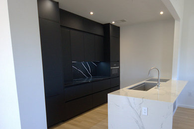 Small minimalist galley eat-in kitchen photo in Raleigh with an undermount sink, flat-panel cabinets, black cabinets, quartz countertops, multicolored backsplash, quartz backsplash, paneled appliances, a peninsula and multicolored countertops